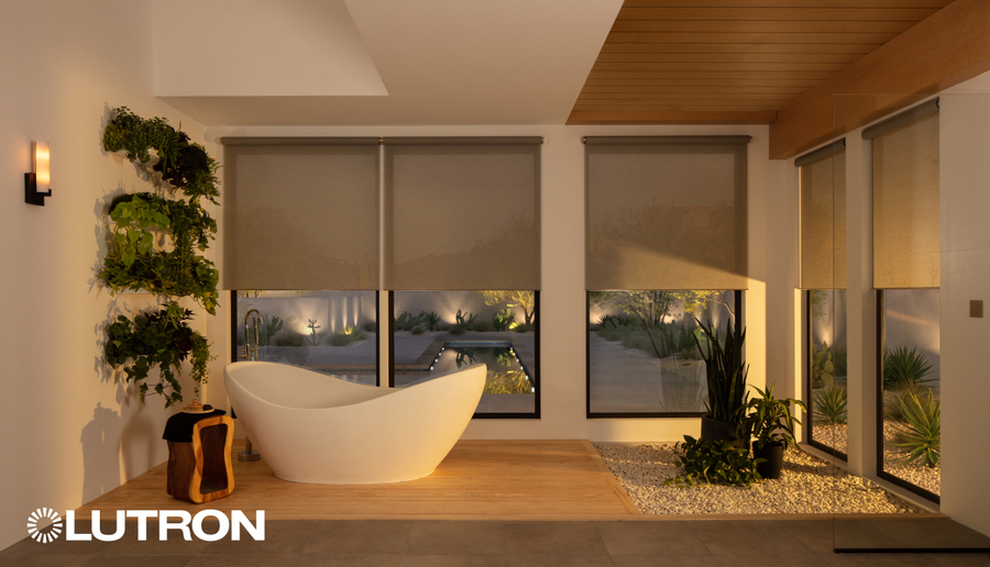 Modern luxury bathroom with a freestanding soaking tub, automated roller shades, floor-to-ceiling windows, warm wood ceiling accents, and soft ambient lighting overlooking a landscaped outdoor space.